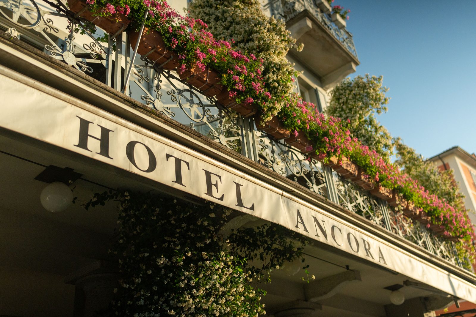 L'insegna Hotel Ancora sopra i portici, con i fiori del balcone